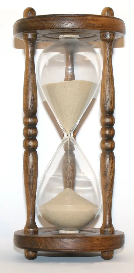 A wooden hourglass with sand running through