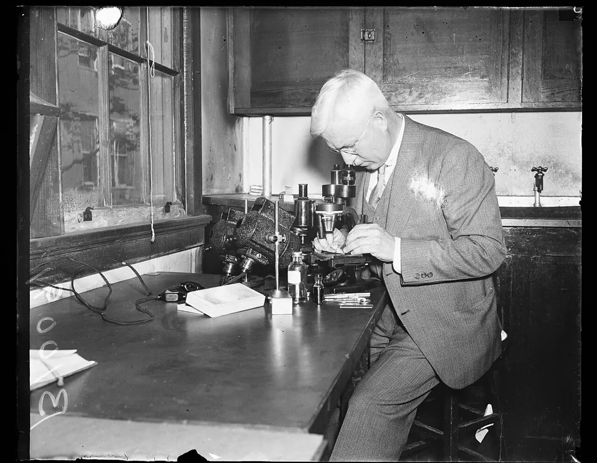 Historical photo of a scientist at a microscope in a laboratory