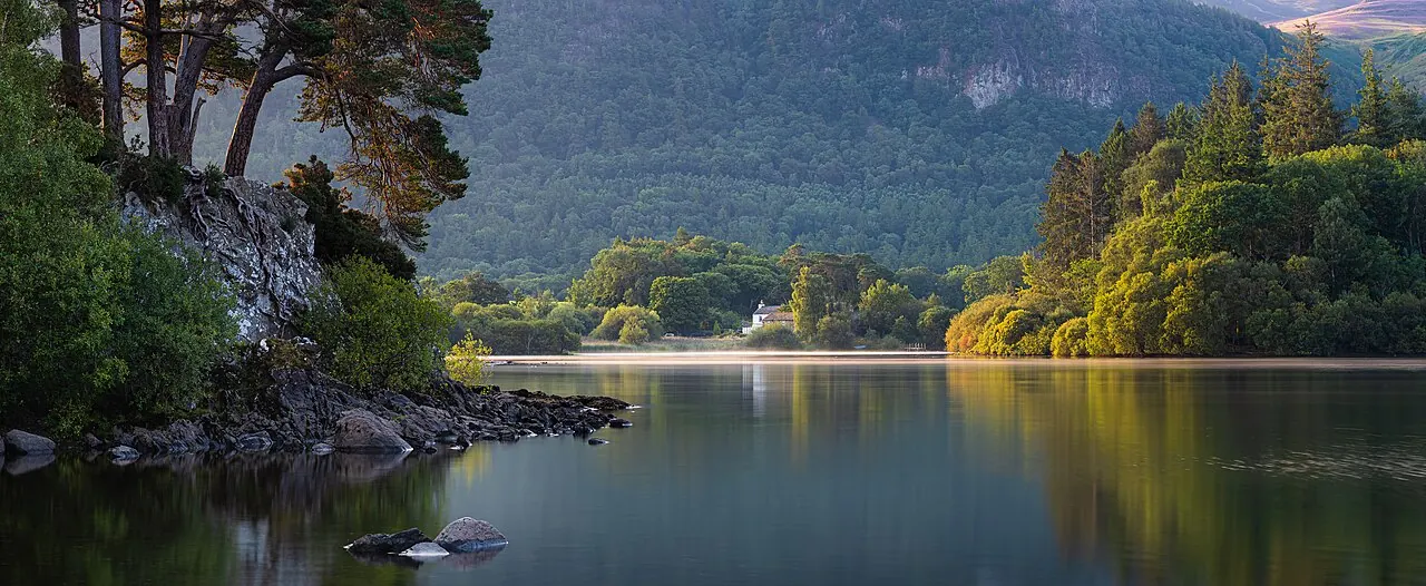 A still lake reflecting a green hillside