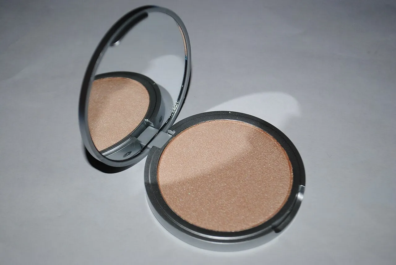 Open compact mirror with a powder highlighter