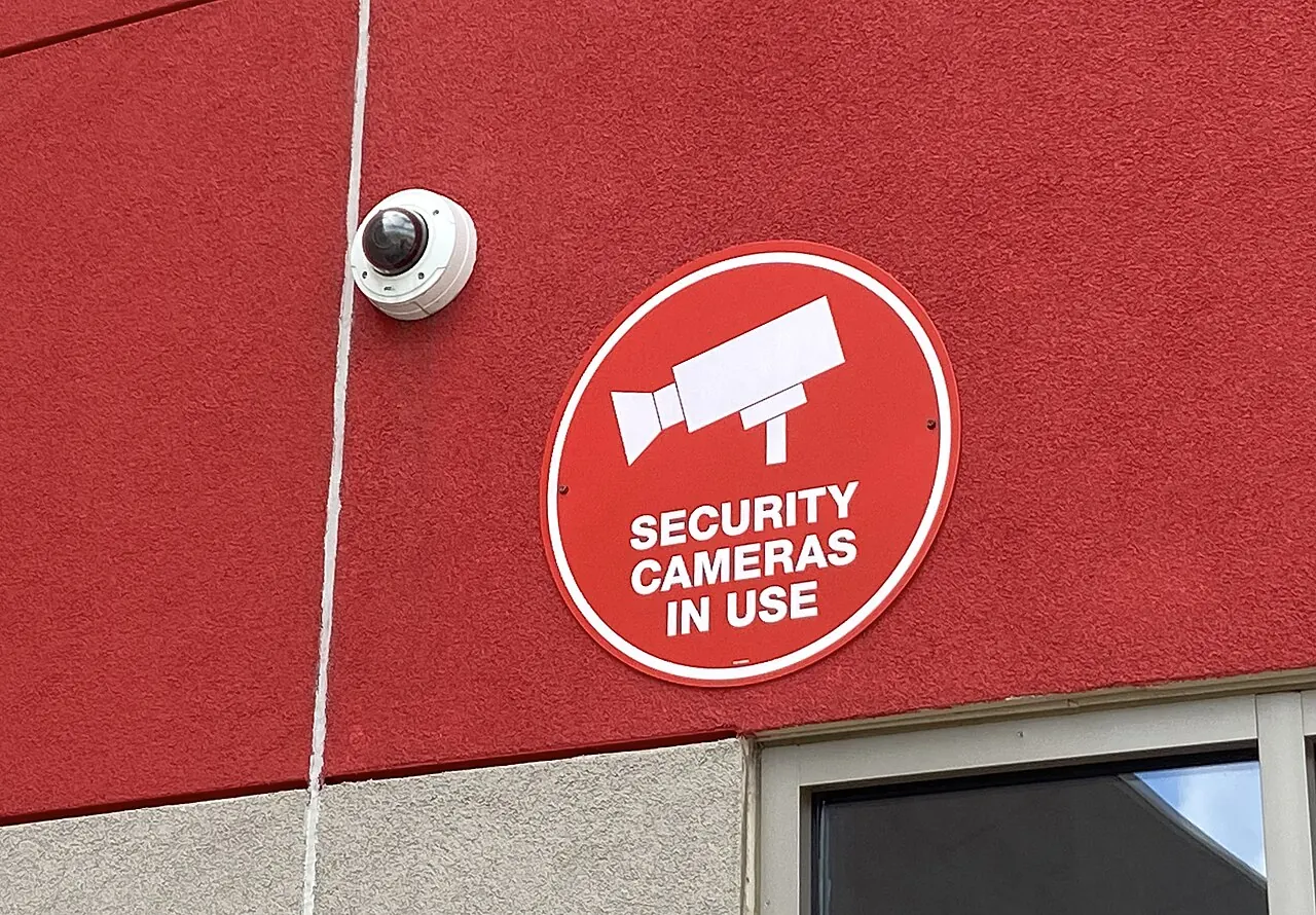 A security camera above a 'Security cameras in use' sign