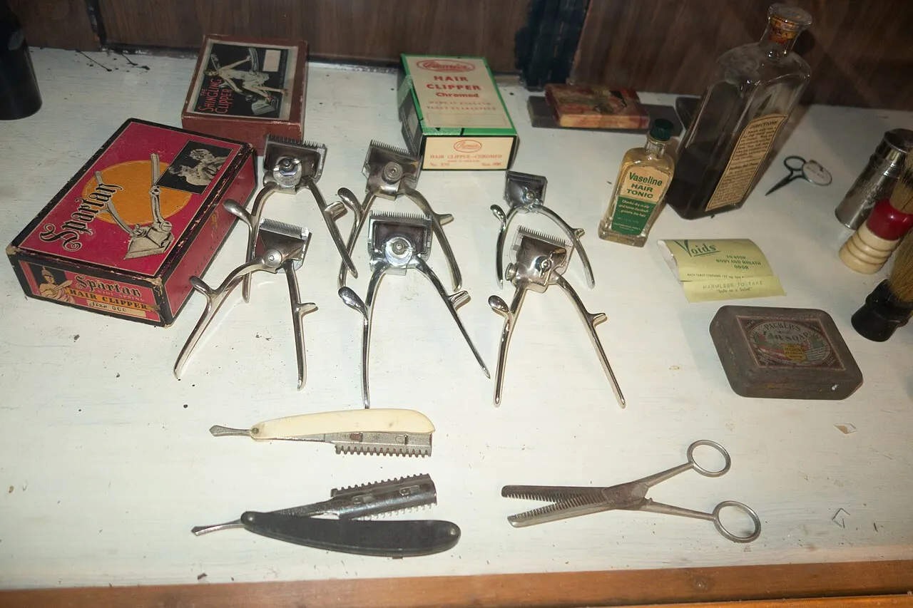Vintage barber tools laid out on a table: hand clippers, razor and scissors