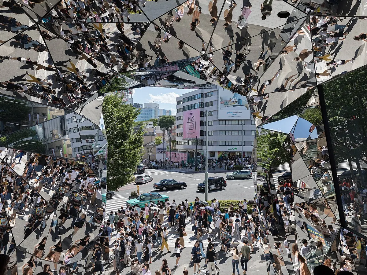A street crowd reflected in a kaleidoscope of mirrored panels
